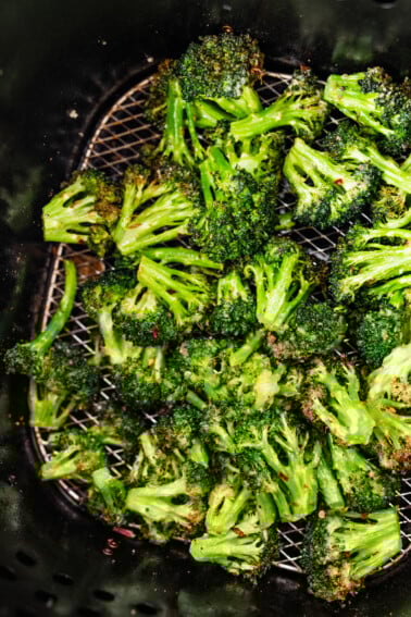 Seasoned air-fried broccoli in an air fryer basket.