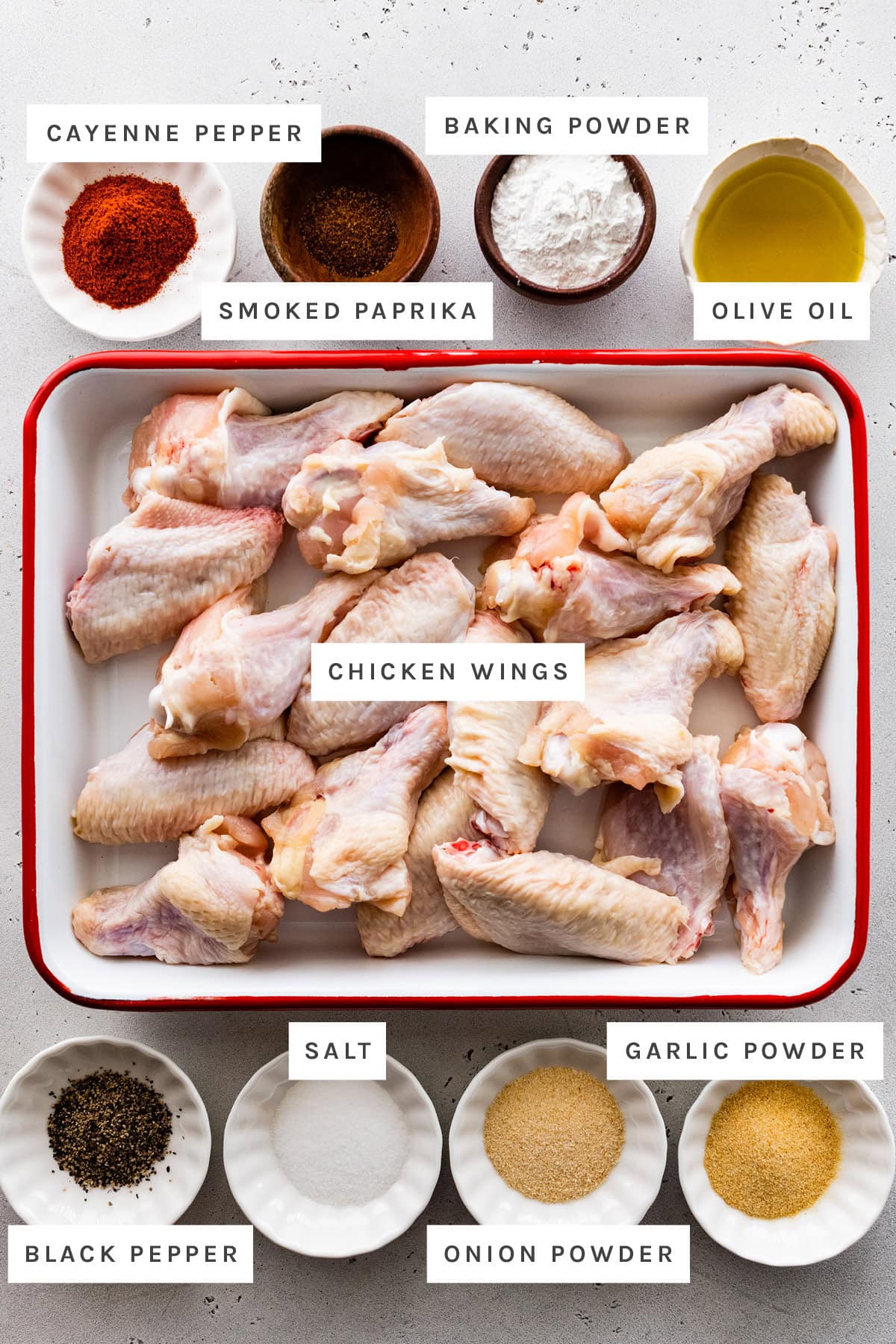 Ingredients measured out to make Air Fryer Chicken Wings: cayenne pepper, smoked paprika, baking powder, olive oil, chicken wings, black pepper, salt, onion powder and garlic powder.