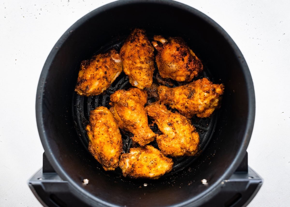 Chicken wings in an air fryer basket after being air fried.