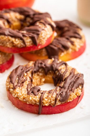 Multiple apple samoas near one another. The slices are topped with a chocolate drizzle.