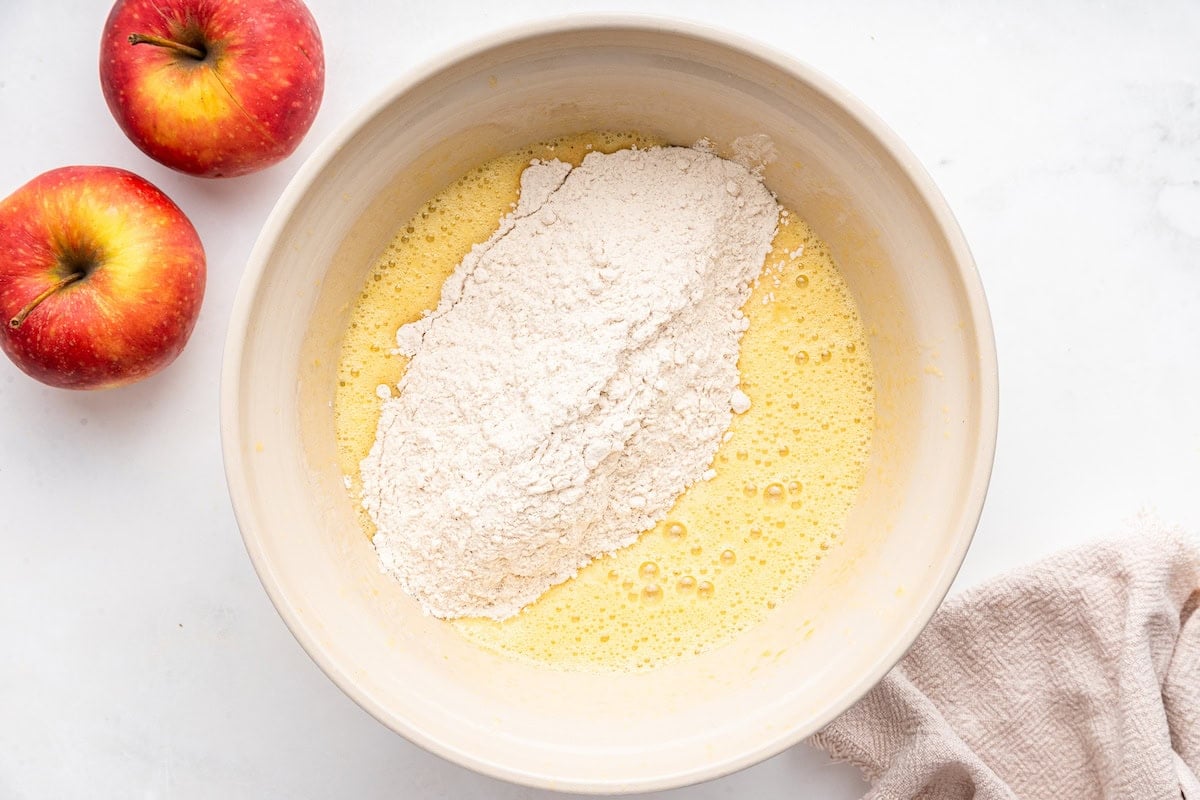 Dry ingredients added to a large bowl of wet ingredients used for an applesauce cake.
