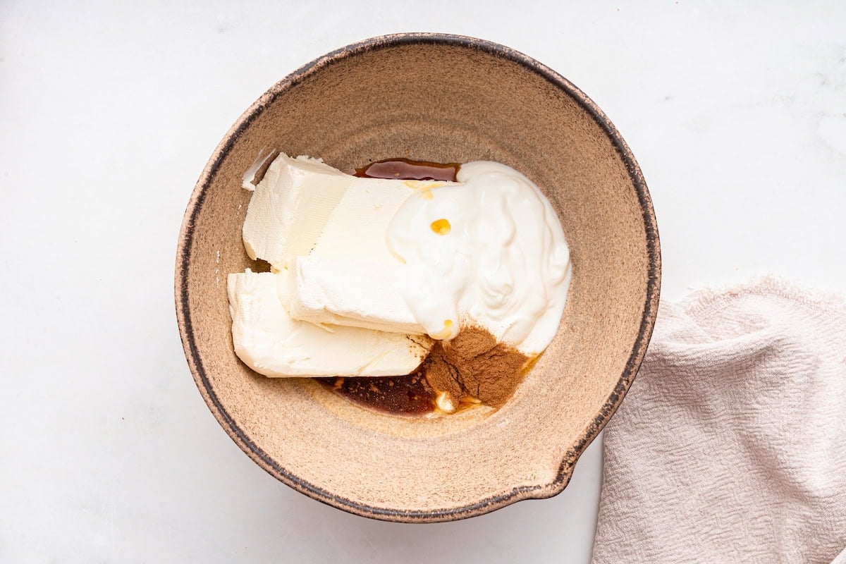 A large mixing bowl of cream cheese, vanilla, and cinnamon.