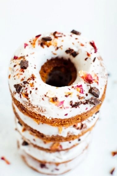 Stack of baked almond flour donuts with rose petals and dark chocolate.