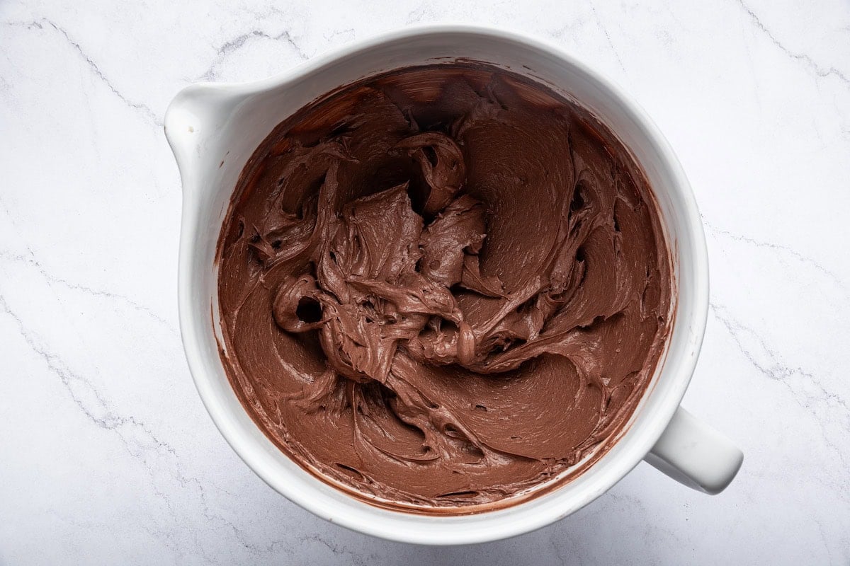 Whipped chocolate buttercream frosting in a mixing bowl.