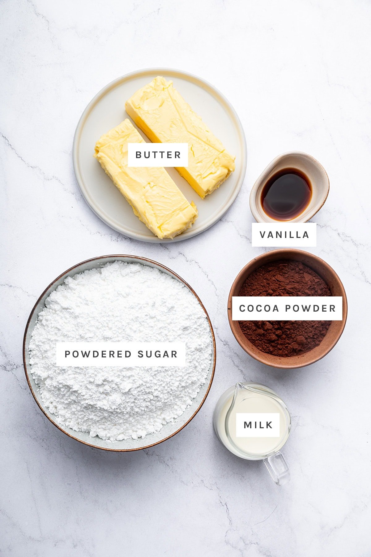 Ingredients measured out to make Chocolate Buttercream: butter, vanilla, powdered sugar, cocoa powder, and milk.