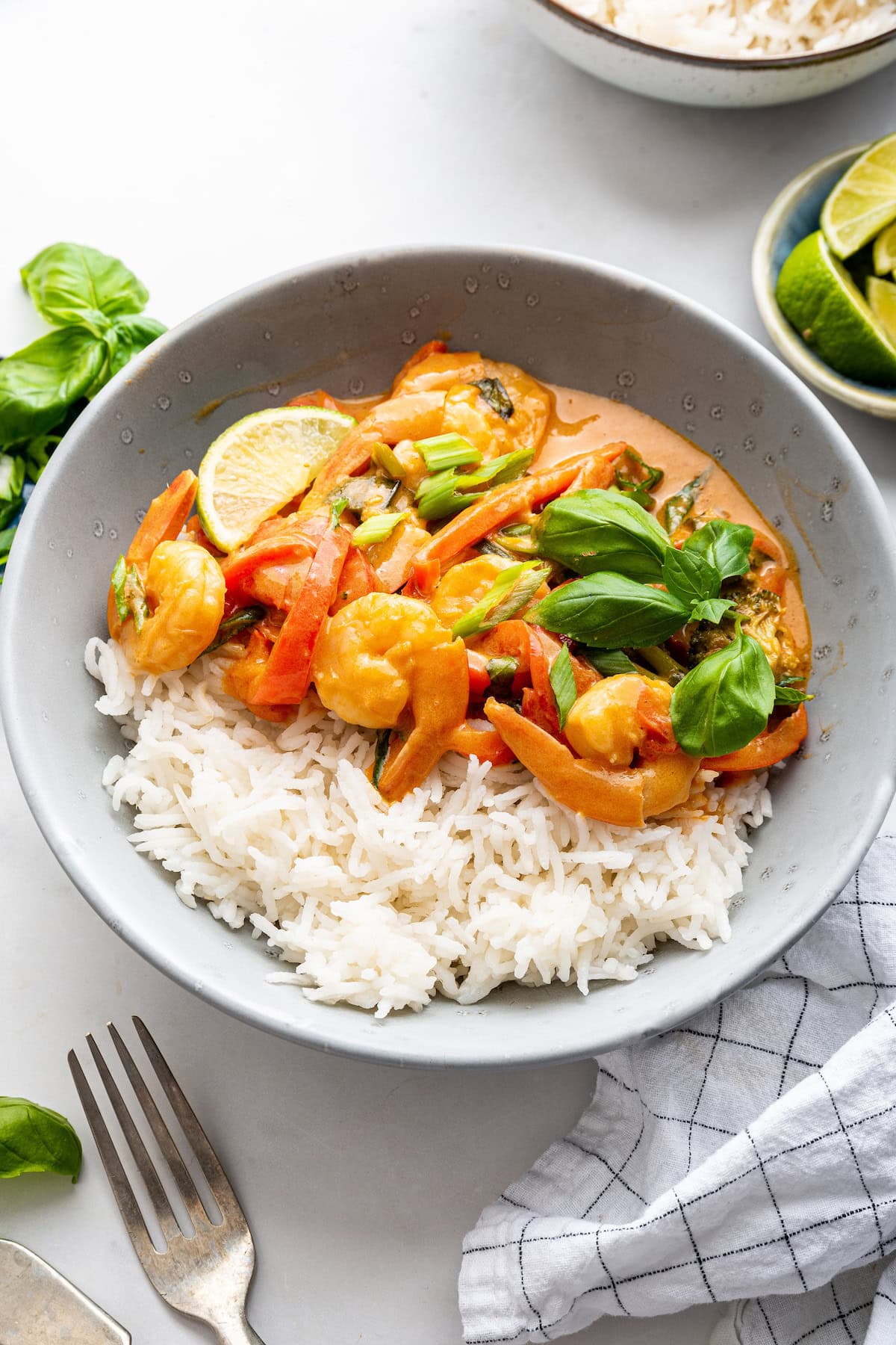 A serving of coconut shrimp curry with white rice in a small bowl.