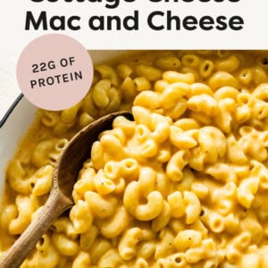 Skillet of mac and cheese with a wood spoon in it.