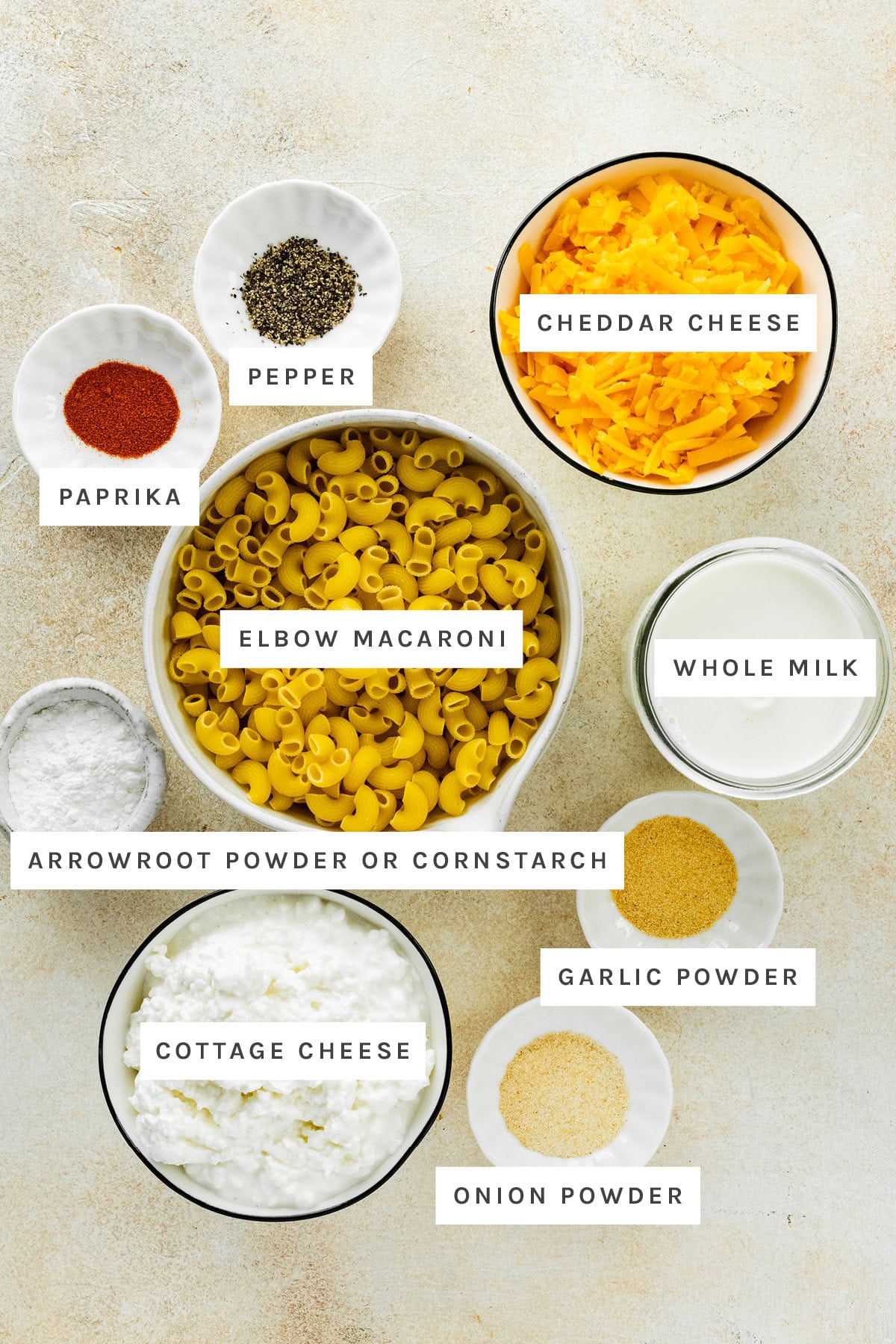 Ingredients measured out to make High Protein Cottage Cheese Mac and Cheese: pepper, paprika, cheddar cheese, elbow macaroni, whole milk, arrowroot powder, garlic powder, cottage cheese and onion powder.