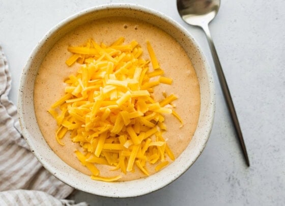 Shredded cheddar cheese in a small bowl with cottage cheese.