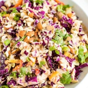 Asian chopped salad in a white bowl with chopped almonds on top.