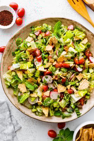 A large bowl of fattoush salad with ingredients like radishes, cherry tomatoes, lettuce, pita chips, and more.