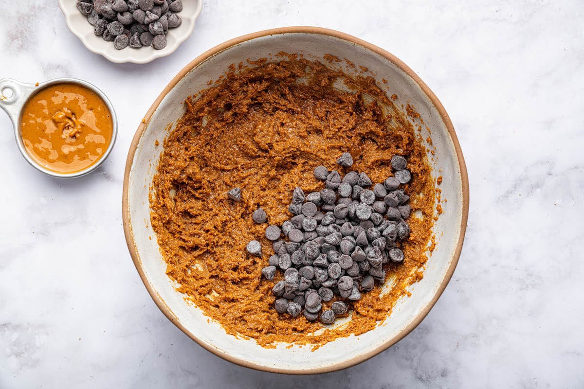 The mixed flourless peanut butter cookies batter in a mixing bowl with chocolate chips.
