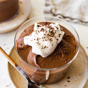 A hard boiled egg chocolate pudding in a glass container, topped with whipped cream and chocolate shavings.