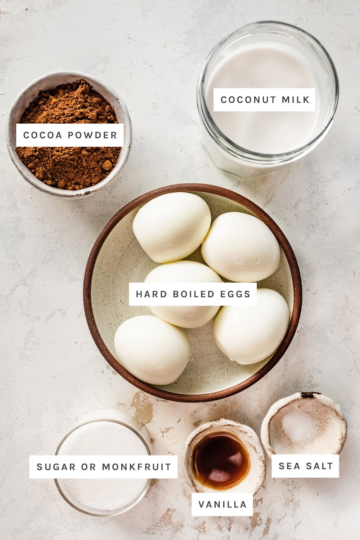 Ingredients measured out to make Hard Boiled Egg Chocolate Pudding: cocoa powder, coconut milk, hard boiled eggs, sugar, vanilla and sea salt.