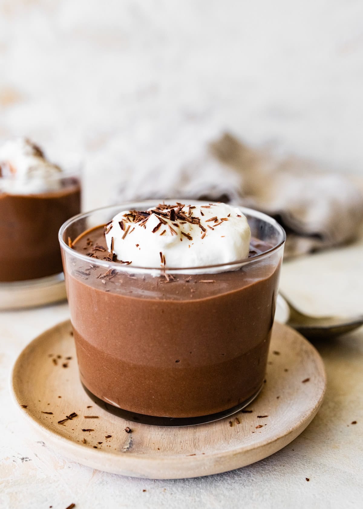 A hard boiled egg chocolate pudding in a glass container, topped with whipped cream and chocolate shavings.