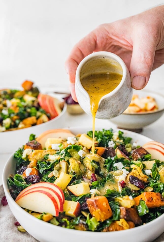 Pouring dressing over a roasted harvest bowl.