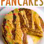 Stack of pumpkin pancakes, drizzled with peanut butter and maple syrup, with a bite taken out of the stack.