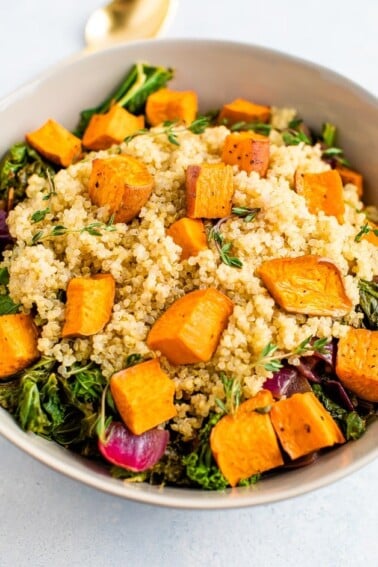 Kale salad with quinoa and roasted sweet potatoes on top.