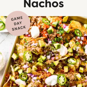 Nachos on a sheet pan topped with ground turkey refried bean mixture, cheese, tomatoes, avocado and jalapeños .