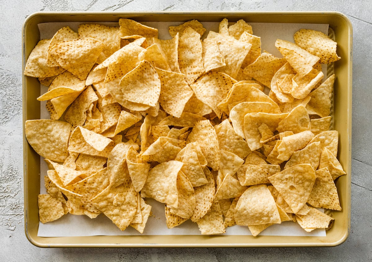 Tortilla chips crowded on a baking tray.