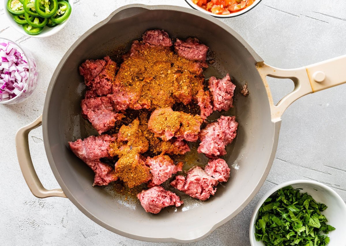 Ground beef with spices cooking in a pan.