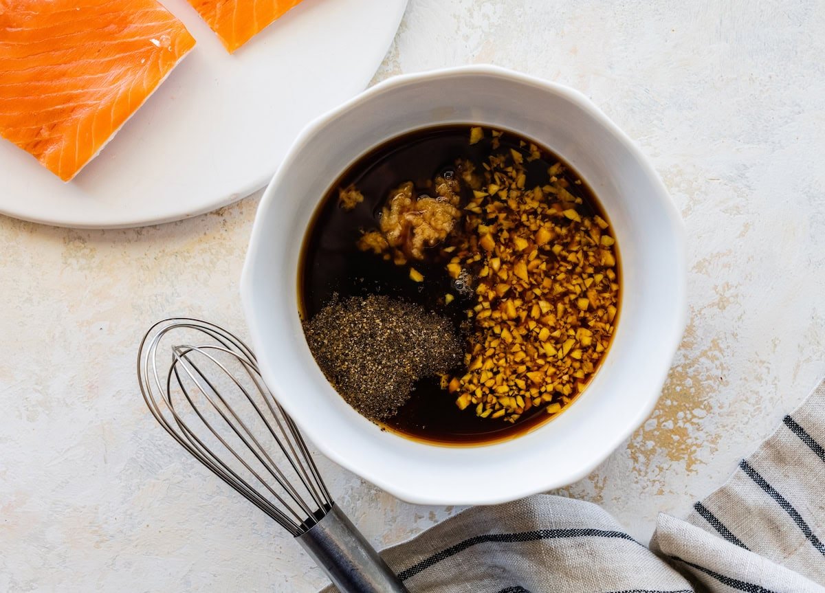 A small bowl of maple syrup, tamari, lemon juice, garlic, ginger and ground pepper.