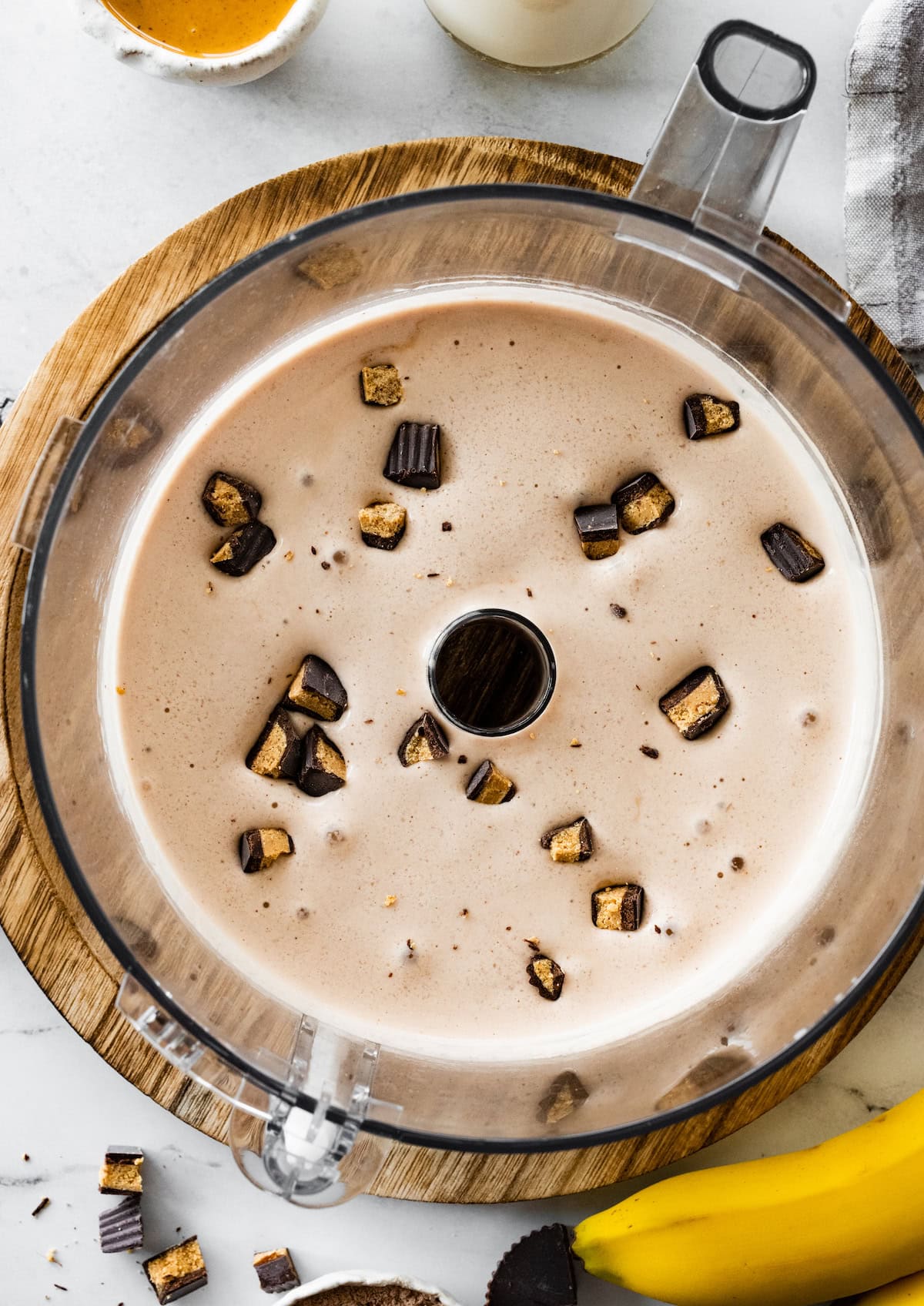 Peanut butter cup protein fluff in a food processor with chunks of peanut butter cups inside.