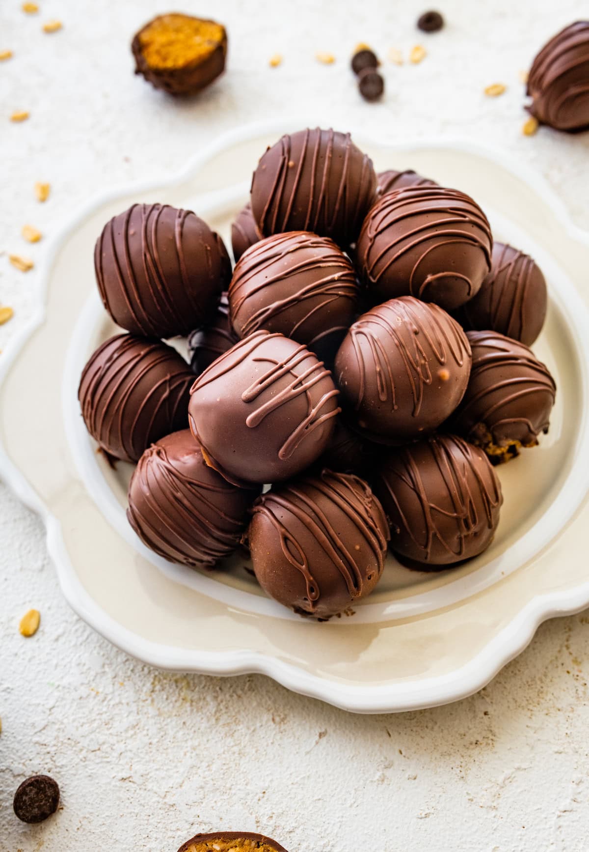 Multiple chocolate covered peanut butter balls stacked on one another on a plate.