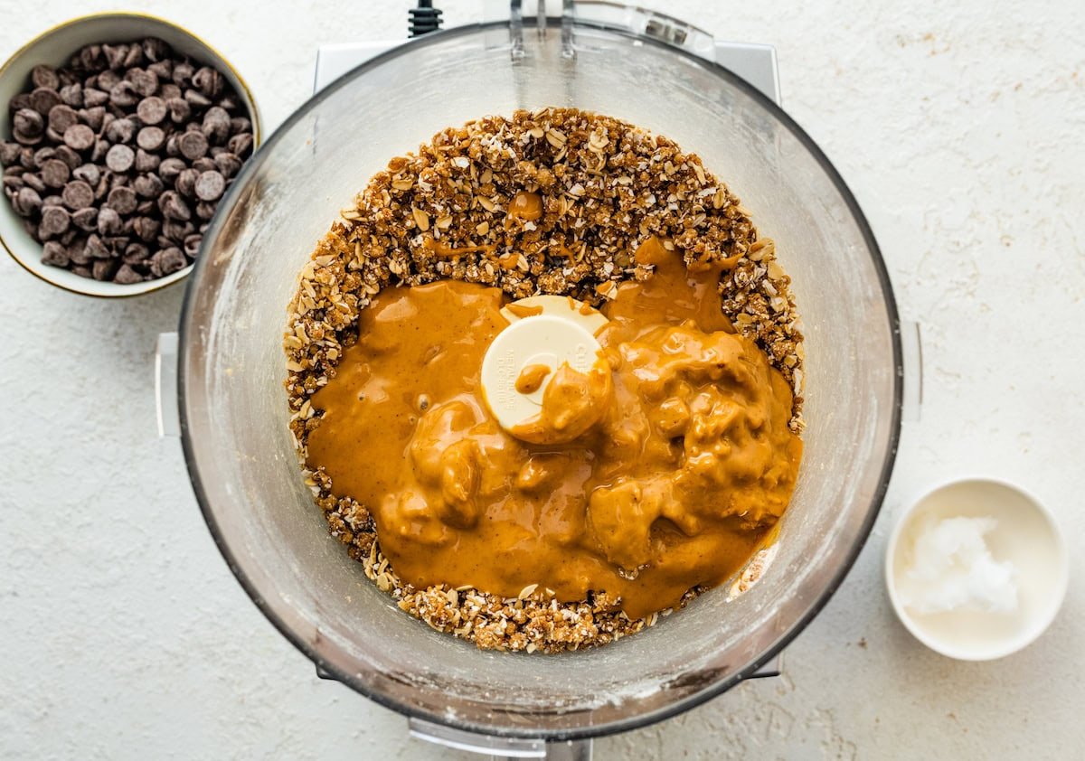 Peanut butter added to a food processor with oats and dates.