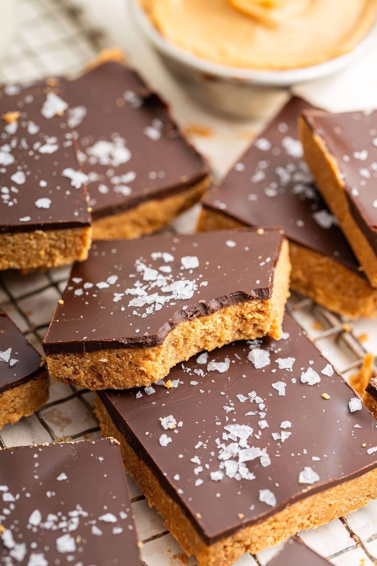 Peanut butter bars stacked on top of each other on a wire cooling rack. One peanut butter bar has a bite taken out of it.