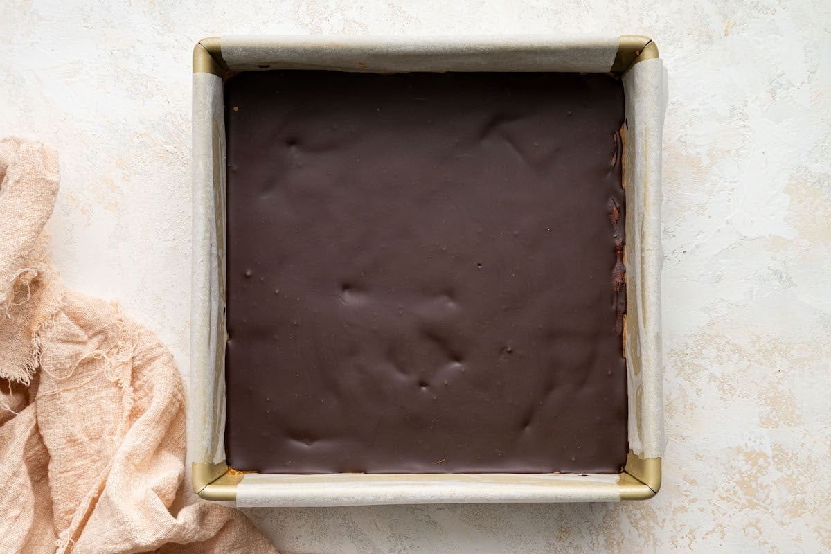 Peanut butter bars uncut in a 8x8 square baking dish after chilling in the fridge.
