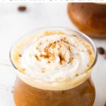 Photo of pumpkin spice latte in a glass mug topped with whipped cream and a sprinkle of pumpkin spice.