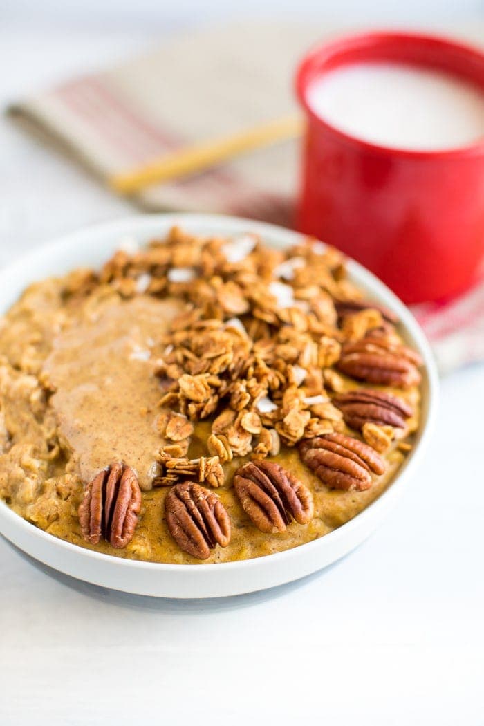This protein pumpkin oatmeal recipe is loaded with pumpkin flavor and protein. The secret is whipping egg whites into the oats while they cook! Protein egg white pumpkin oatmeal topped with peanut butter, granola, and pecans.