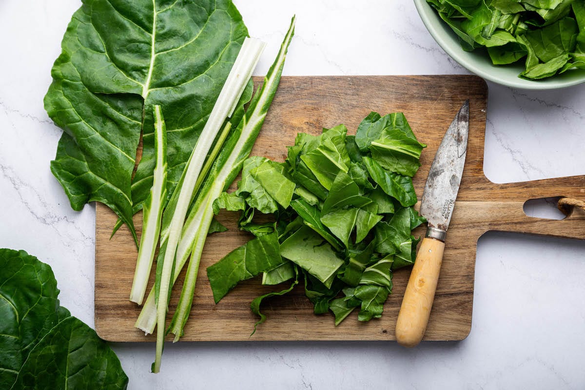 Chopped swiss chard on a wooden cutting board next to a knife.