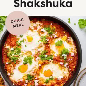 Shakshuka in a skillet-- tomato based veggie skillet topped with sunny side up eggs.
