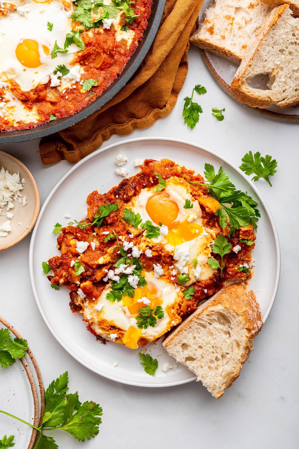 A serving of shaksuka on a plate with a side of bread.
