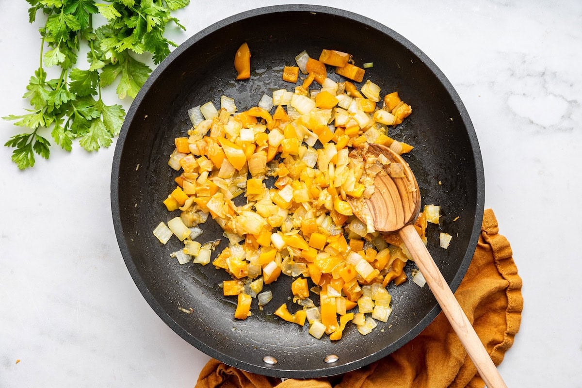 Yellow bell pepper and onion cooking in a pan.