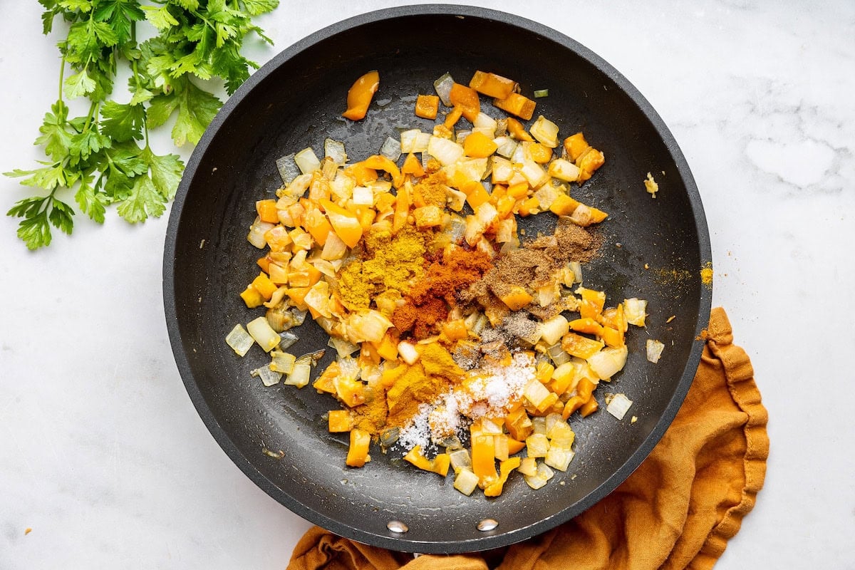 yellow bell pepper with onion, and other spices in a pan.