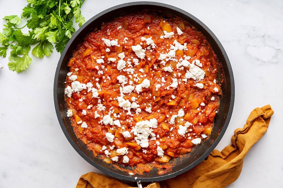 Yellow bell pepper with onion and other spices mixed with a tomato sauce and topped with feta cheese.