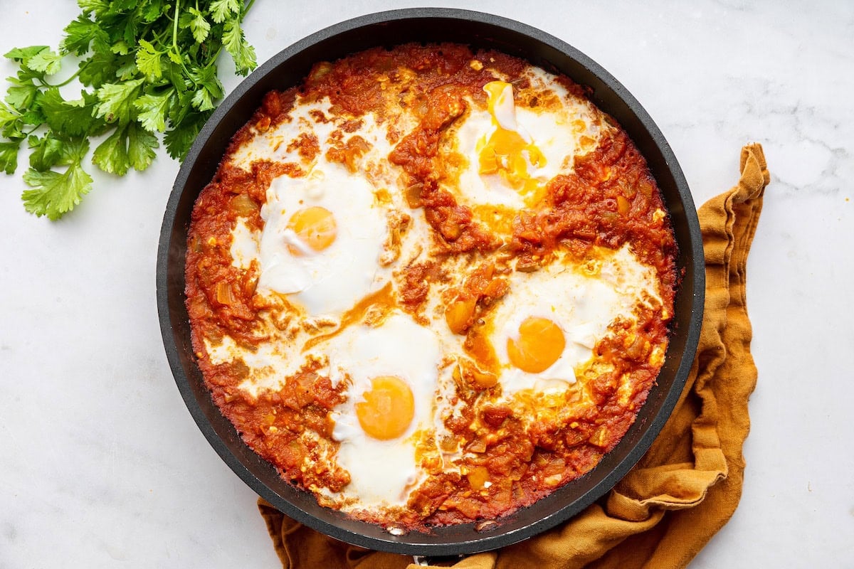 Four poached eggs in a pan with a tomato sauce.