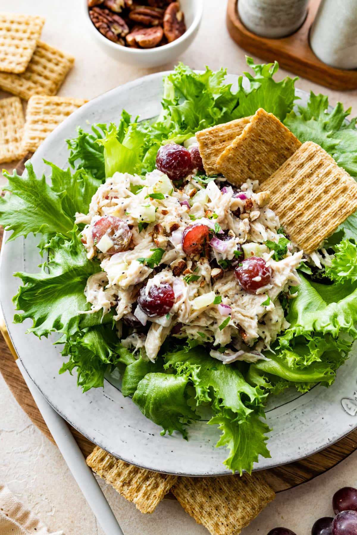 A serving of sonoma chicken salad on a bed of lettuce with crackers on the side.