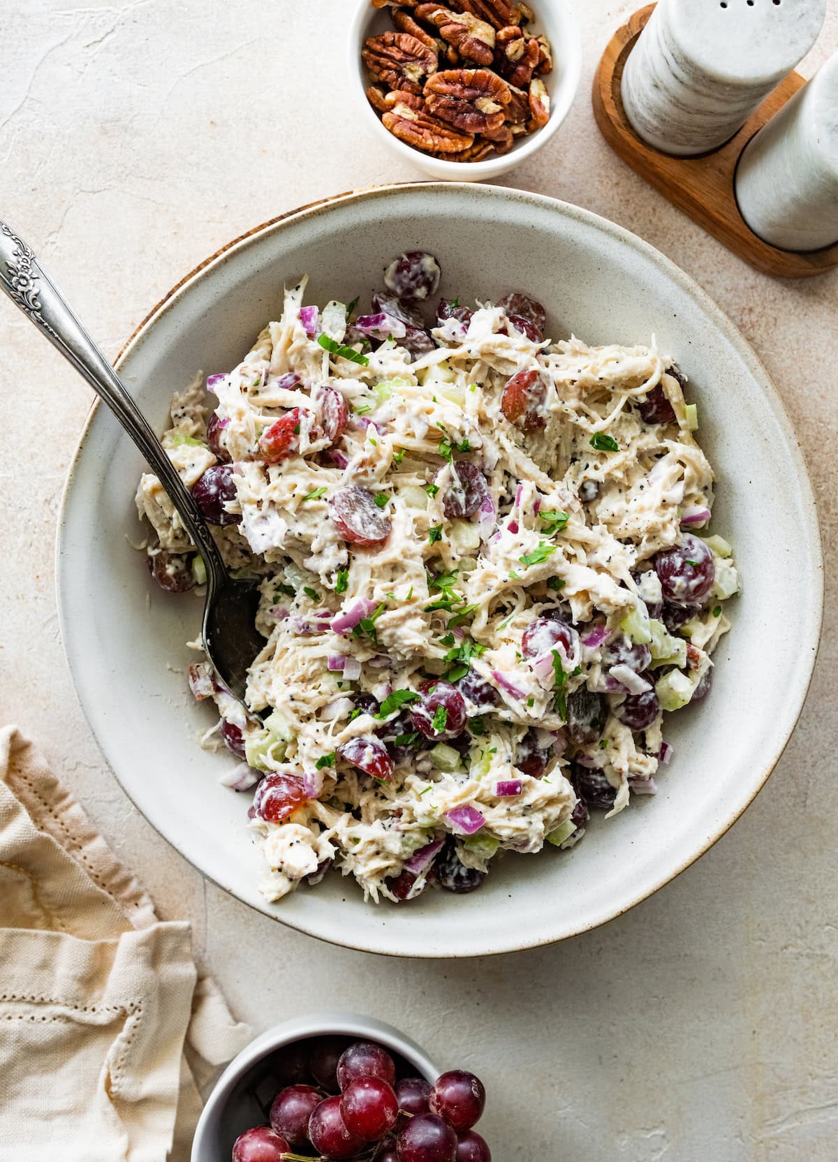 A sonoma chicken salad in a large bowl with ingredients like grapes, shredded chicken, pecans, and more.