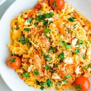 Plate of spaghetti squash with feta, basil and tomatoes.