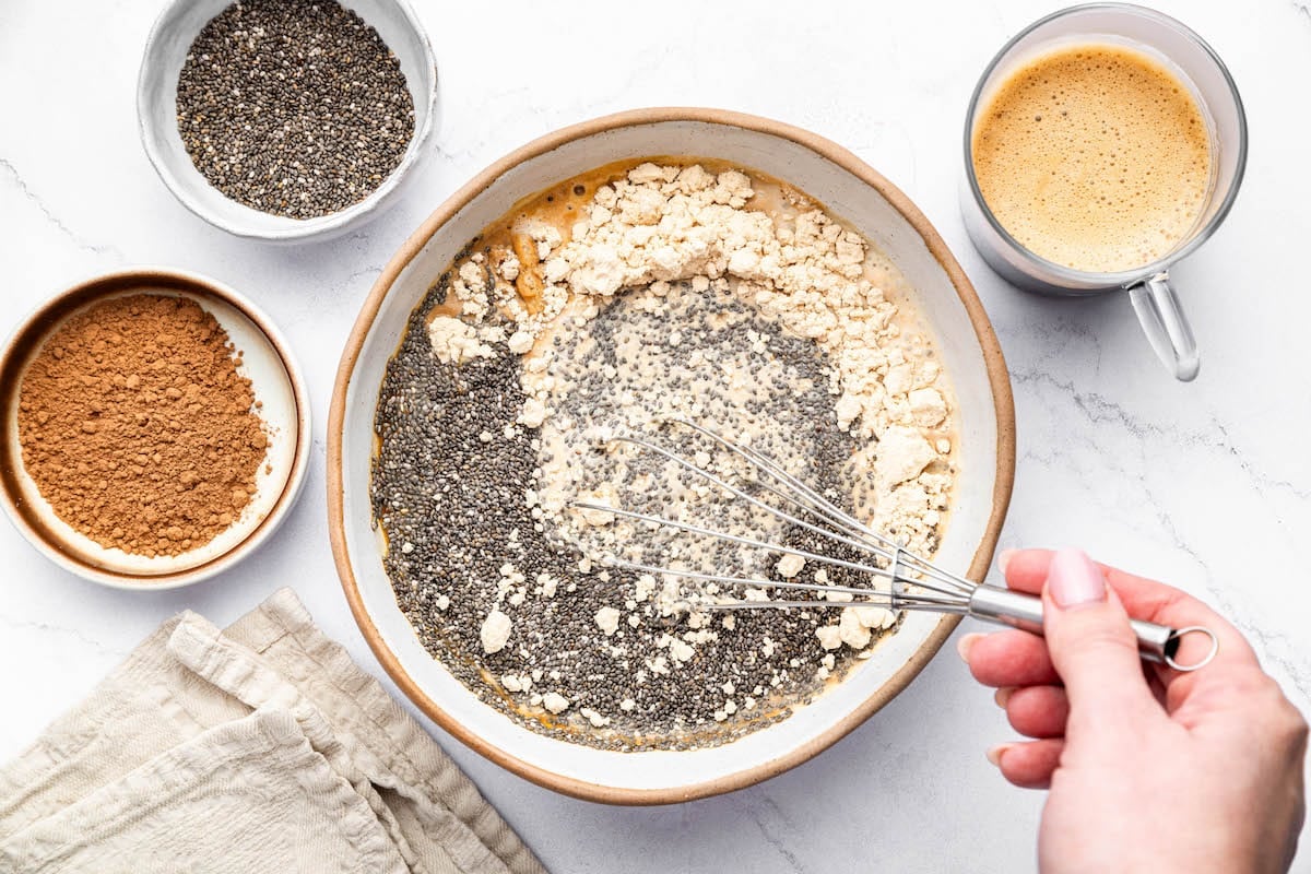 A whisk being used to combine all the ingredients in a large bowl used to make tiramisu chia pudding.