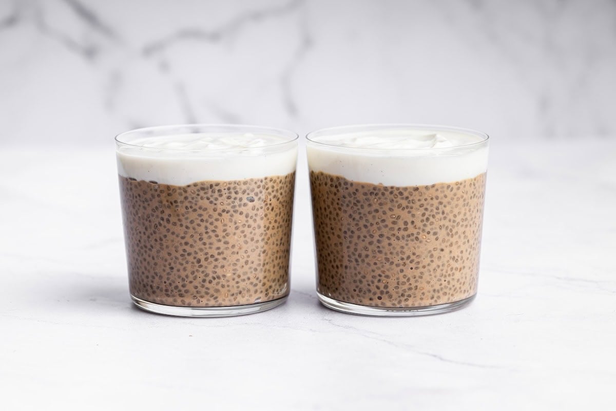 Two glass cups of tiramisu chia pudding topped with yogurt.