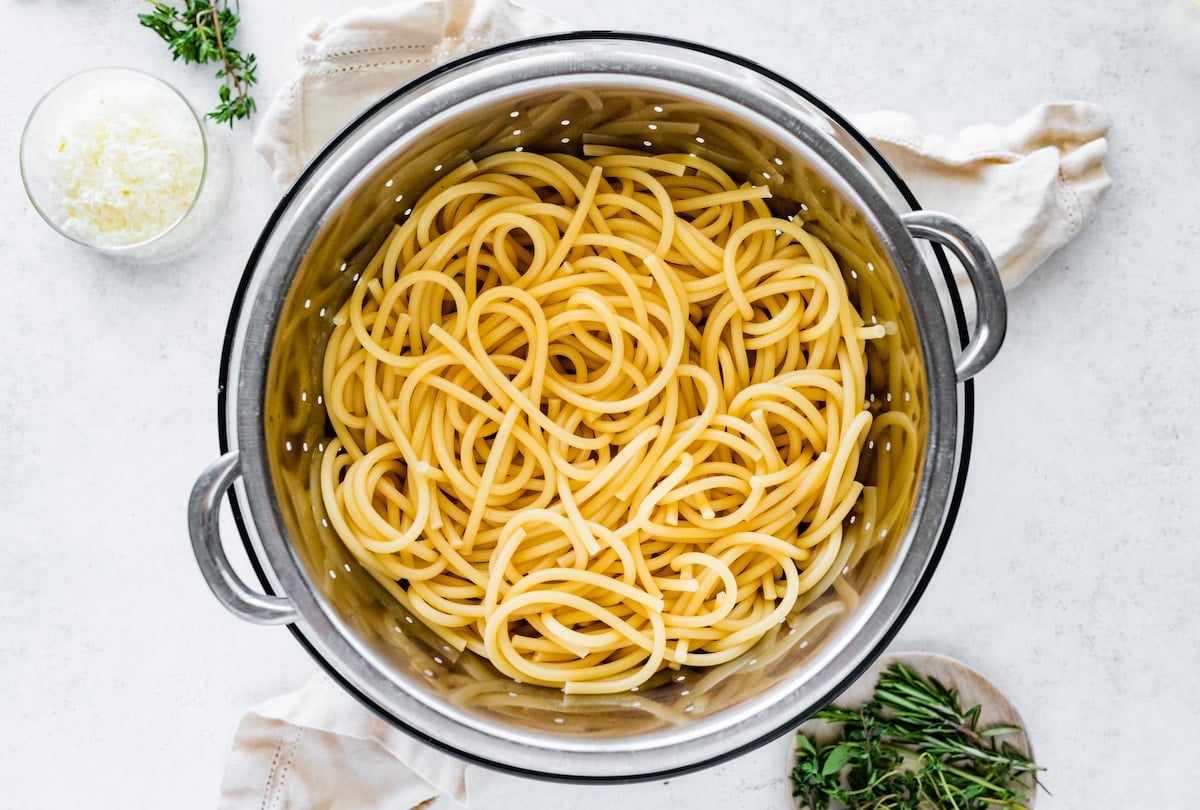 Cooked spaghetti in a metal colander.