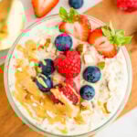 Jar of protein overnight oats topped with berries, almonds and peanut butter.