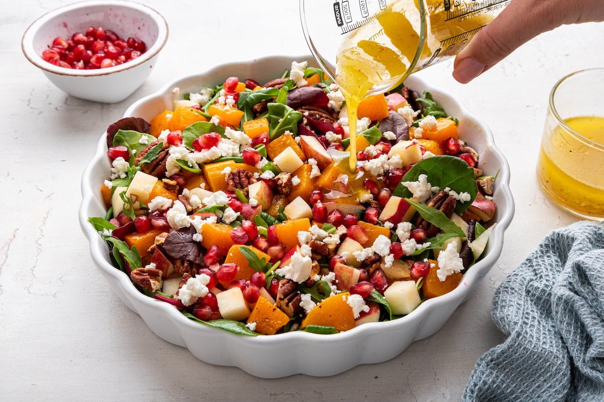 Dressing being poured onto the winter salad.