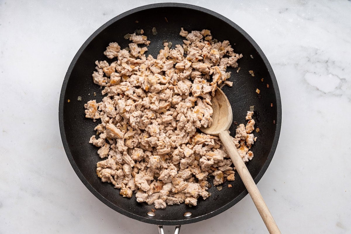 Cooked turkey in a skillet with a wooden spoon.