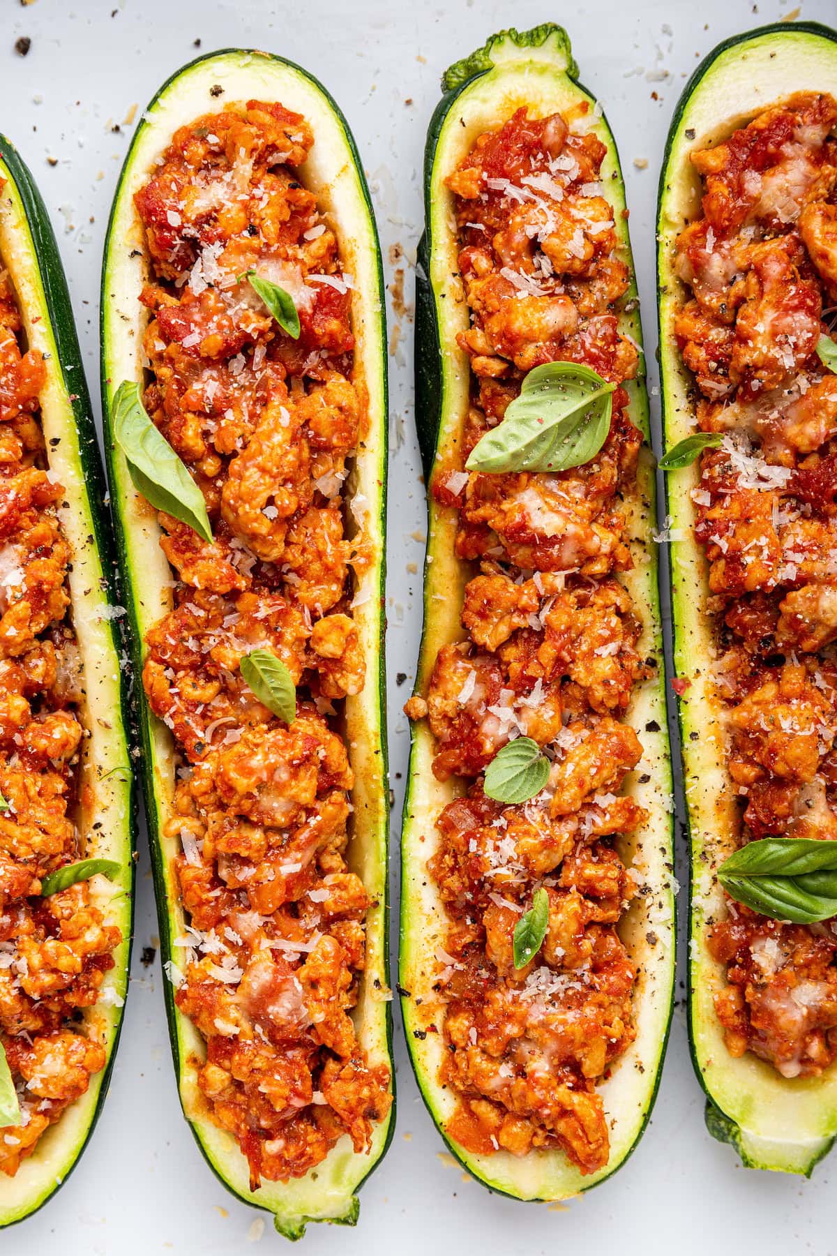 Four turkey zucchin boats topped with fresh herbs and spices.